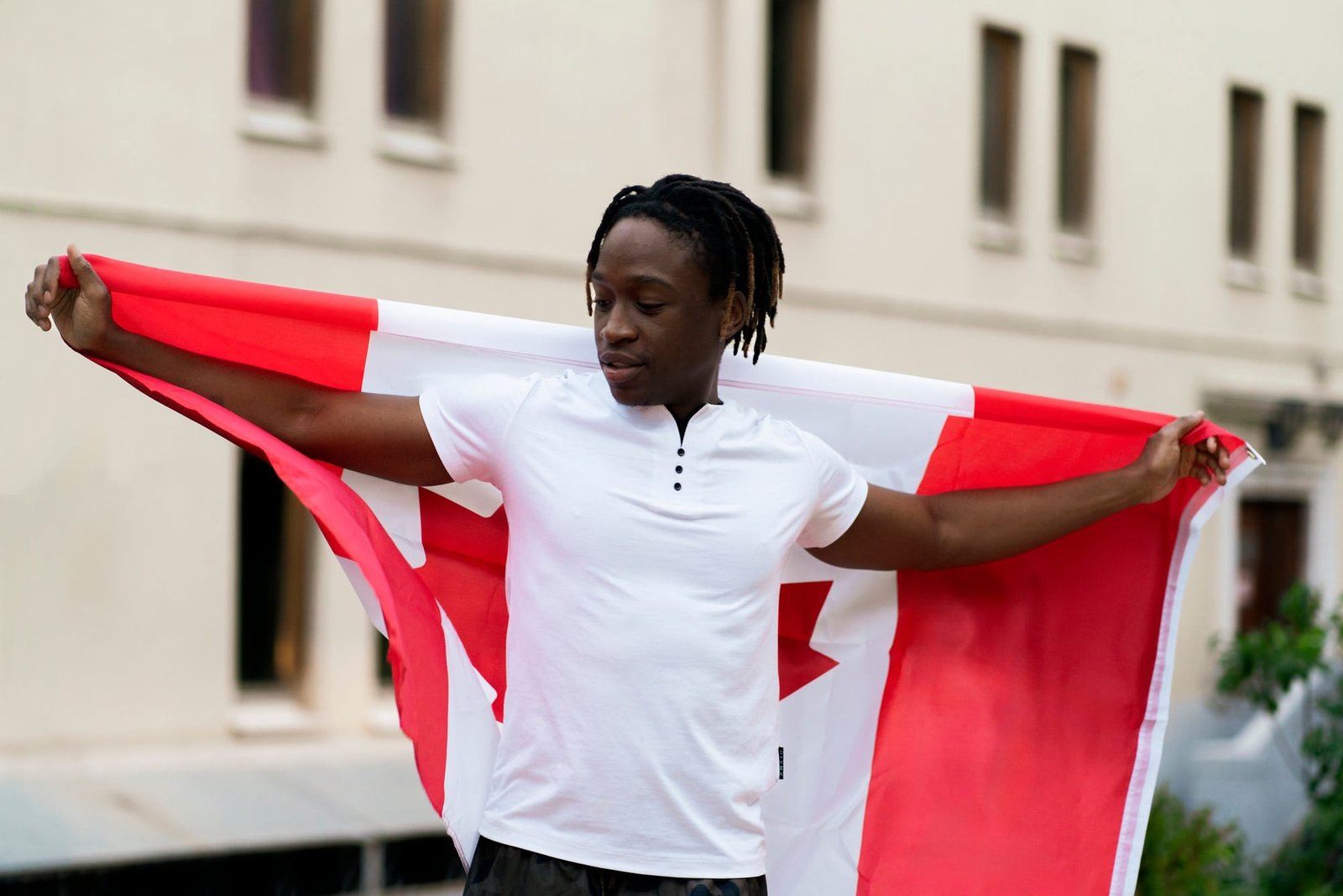 a black male person holding a flag of canada outdoors, concept of patriotism and independence