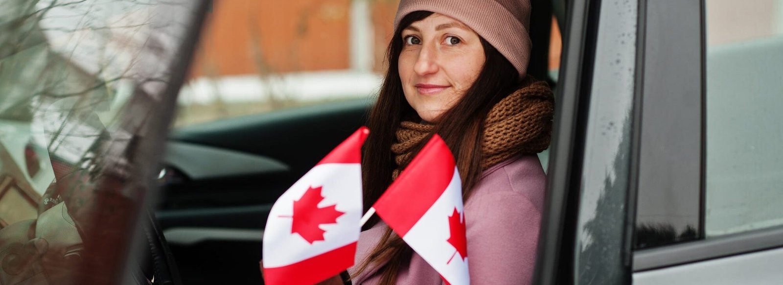 Young woman with Canada flag siting on car. Young woman with Canada flag siting on car.
