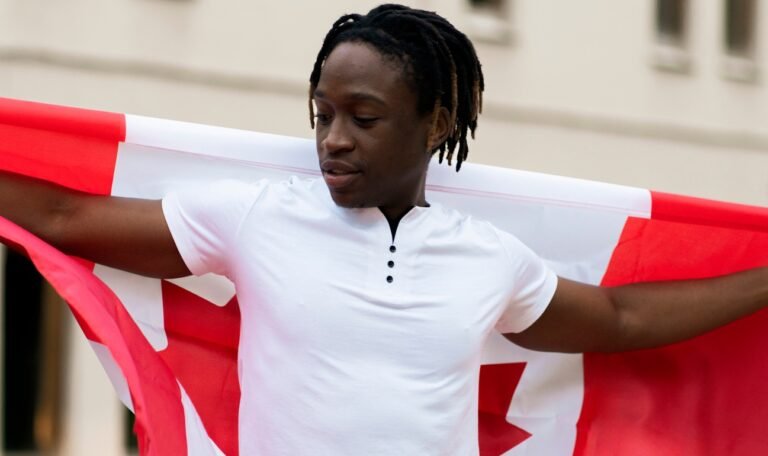 a black male person holding a flag of canada outdoors, concept of patriotism and independence