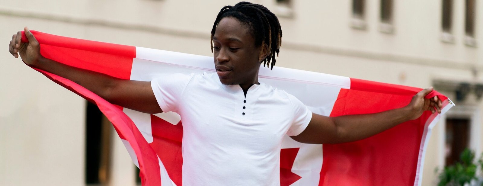 a black male person holding a flag of canada outdoors, concept of patriotism and independence a black male person holding a flag of canada outdoors, concept of patriotism and independence