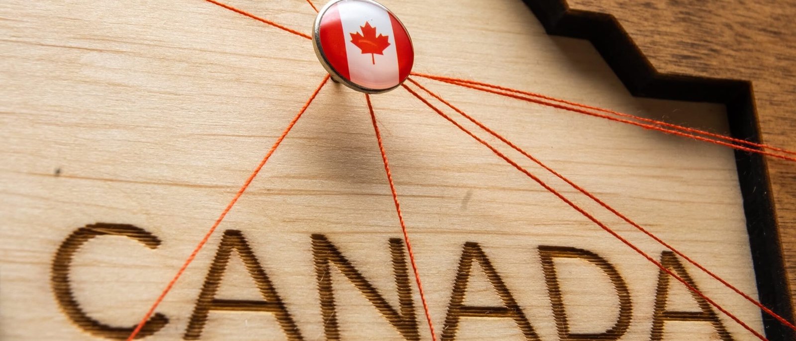 Canada flag on the pin with red thread showed the paths on the wooden map. Canada flag on the pin with red thread showed the paths on the wooden map.