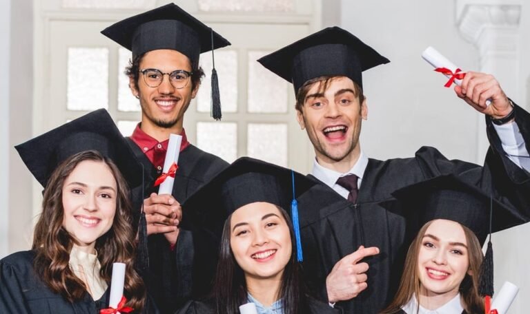 cheerful group of students in graduation gowns holding diplomas