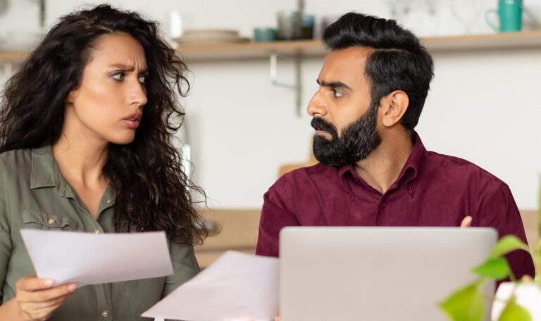 Worried arab spouses sitting at desk in front of laptop, checking bills, working on family budget in