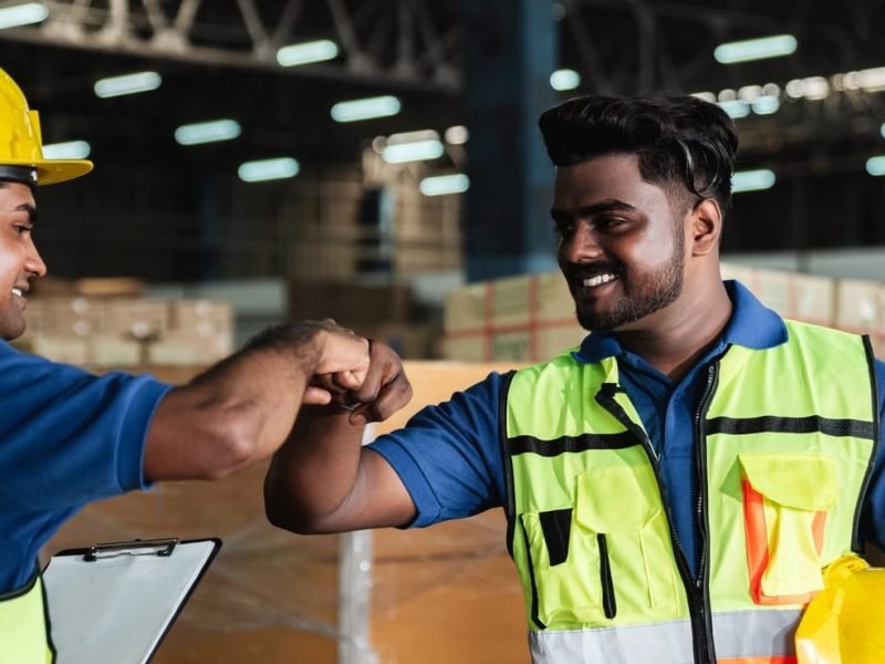 Group warehouse workers shake hands to celebrate and be happy in the warehouse.